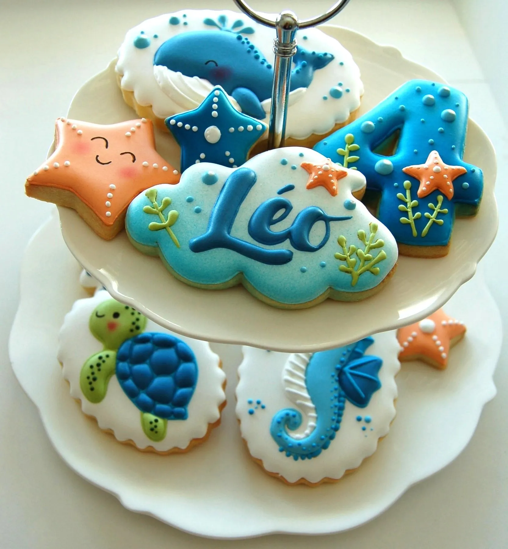 Biscuits personnalisés thème océan : nuage au prénom, chiffre, tortue et étoiles de mer sur un présentoir à étages