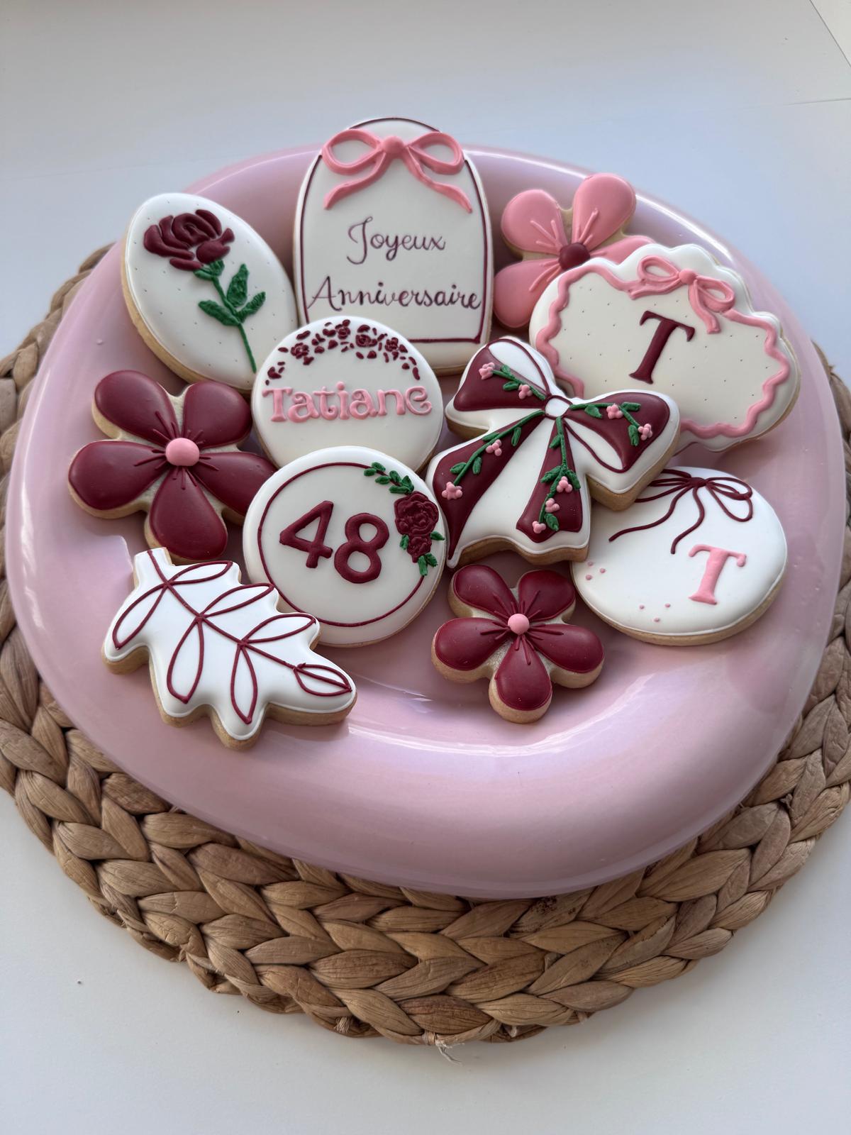 Plateau rose garni de biscuits d'anniversaire : fleurs bordeaux, nœuds, monogramme T et chiffre 48