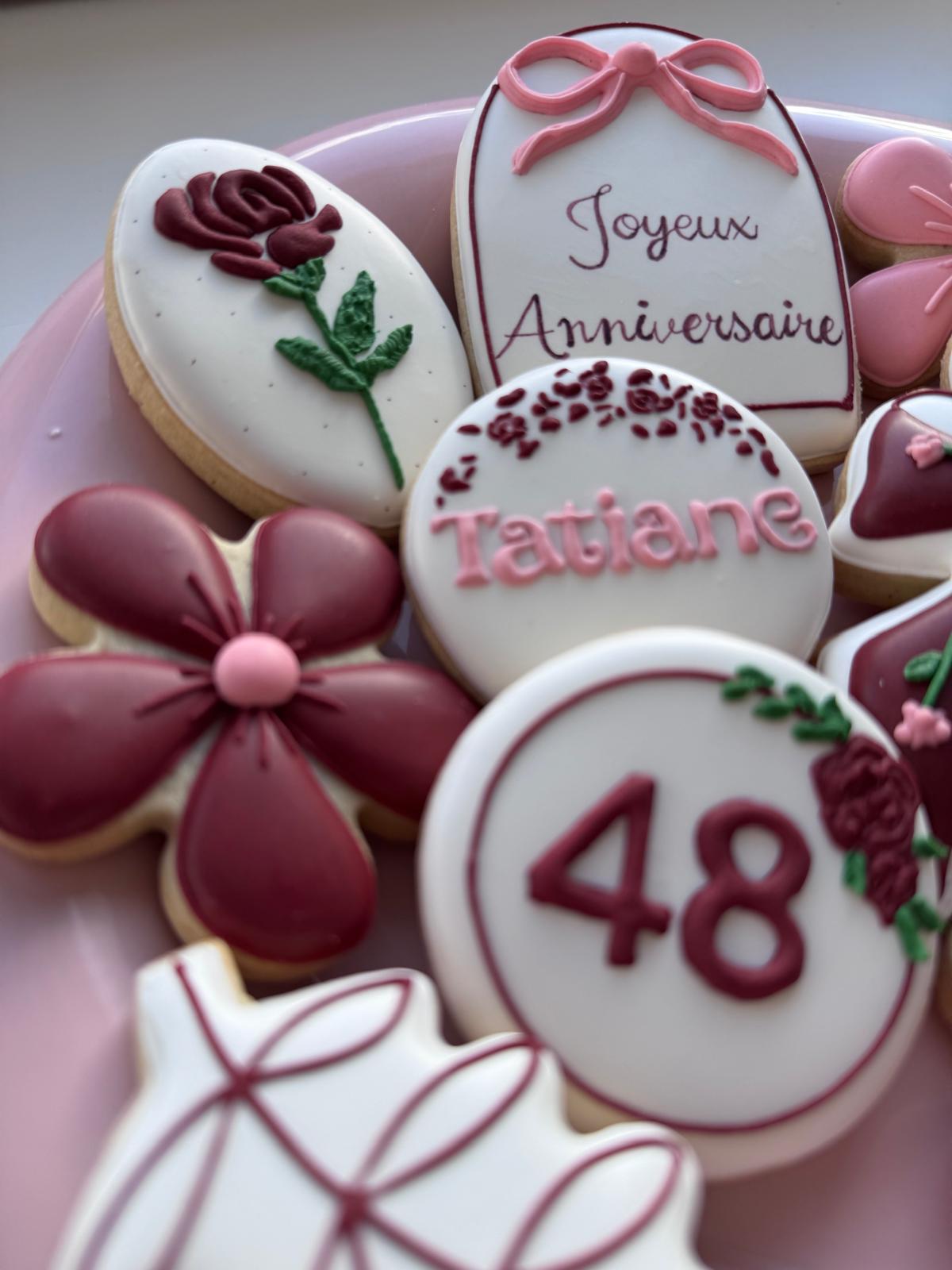 Biscuit rond au chiffre 48, encadré de fleurs bordeaux et d'un ballon dessiné au glaçage