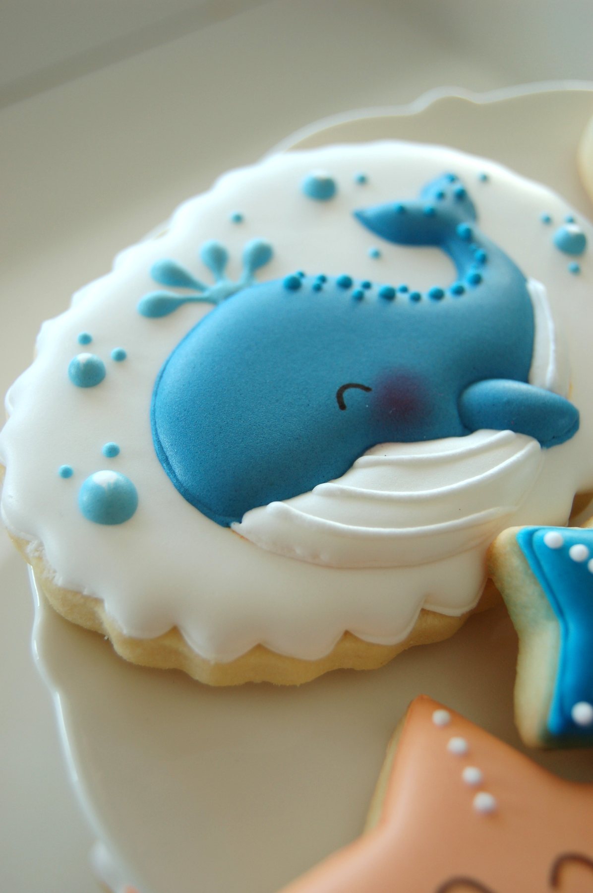 Biscuit baleine bleue posée sur une vague, décorée au glaçage royal