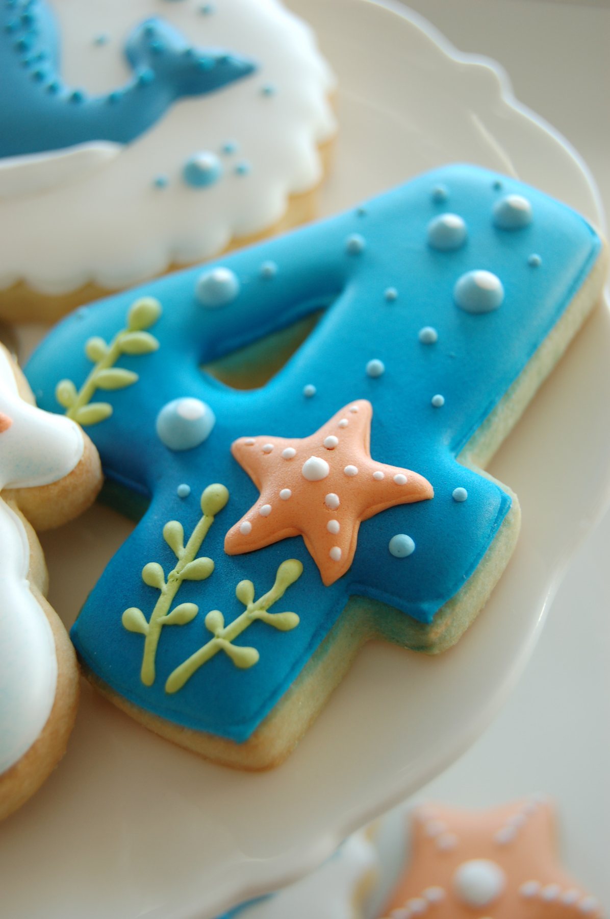 Biscuit chiffre 4 bleu décoré de bulles, d'algues vertes et d'une étoile de mer corail