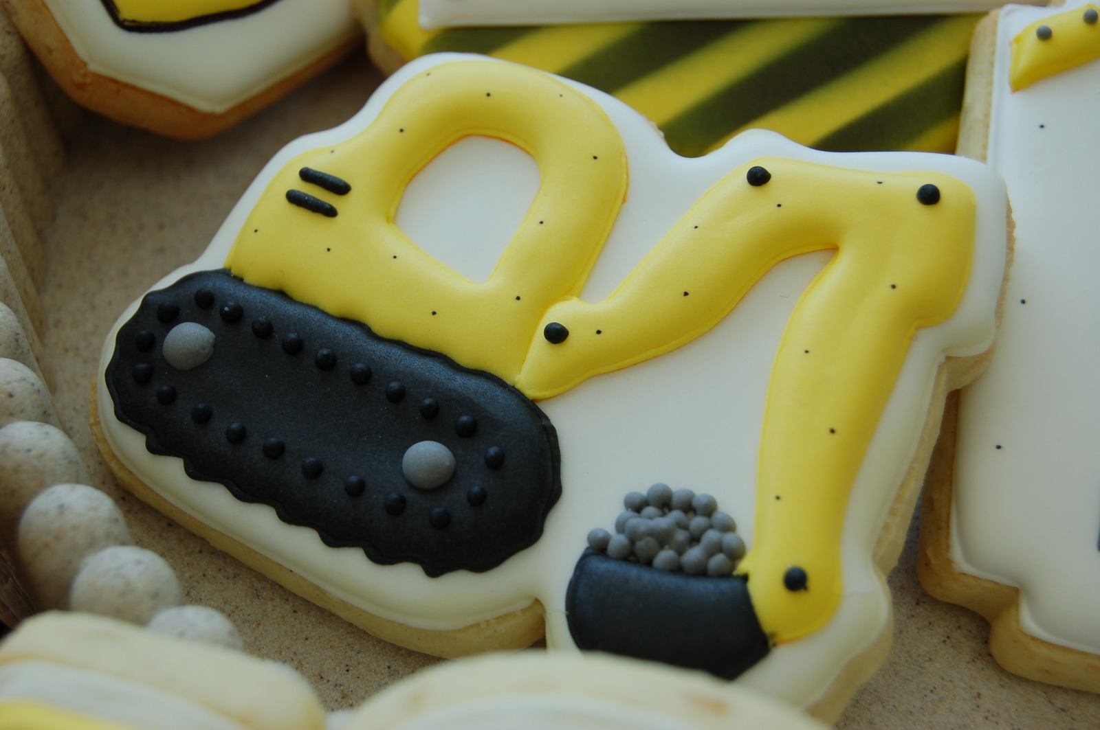 Biscuit pelleteuse jaune et noire posé devant des biscuits rayés jaune et noir