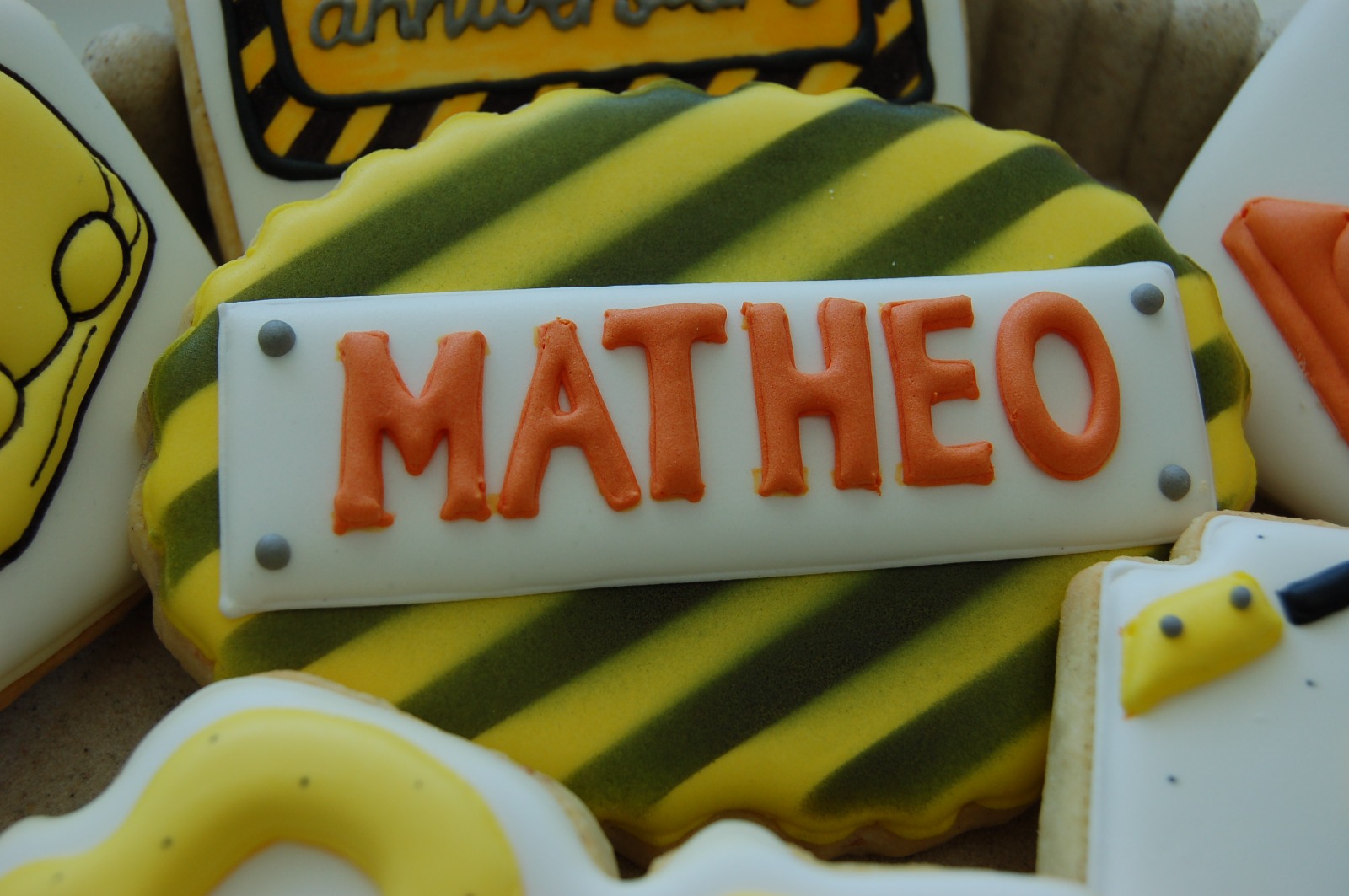Gros plan sur la plaque de chantier au prénom Mathéo, lettrage orange sur glaçage blanc