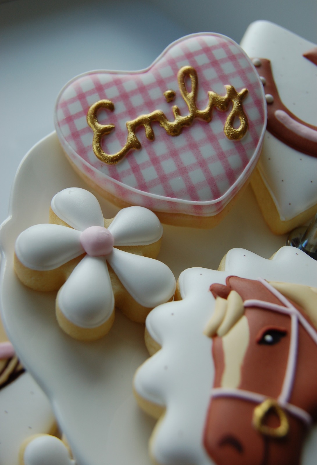 Biscuit cœur en vichy rose au prénom calligraphié à l'or, à côté d'une tête de poney bridée