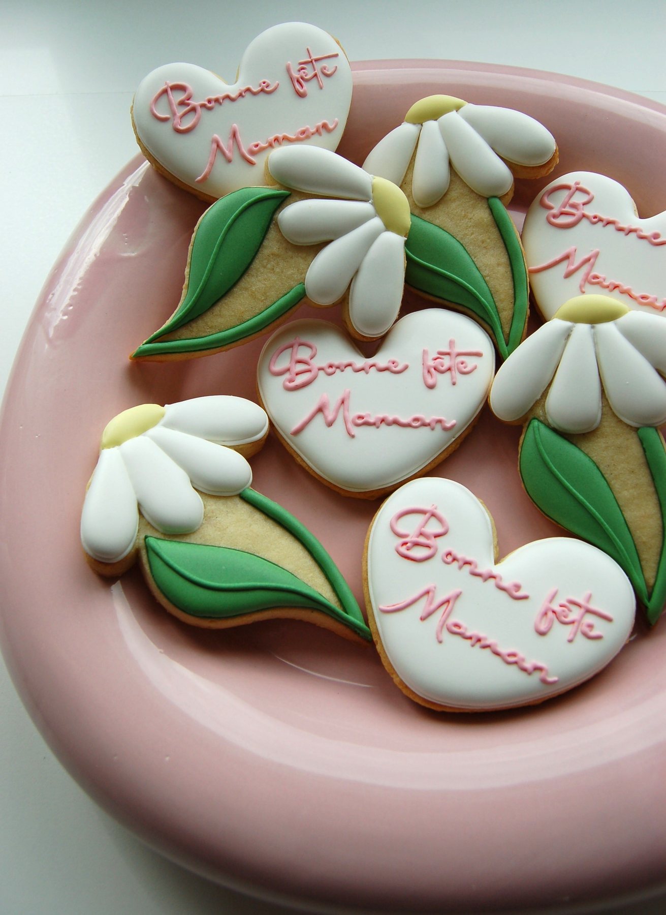Assiette rose garnie de biscuits cœur Bonne fête Maman et de marguerites en glaçage