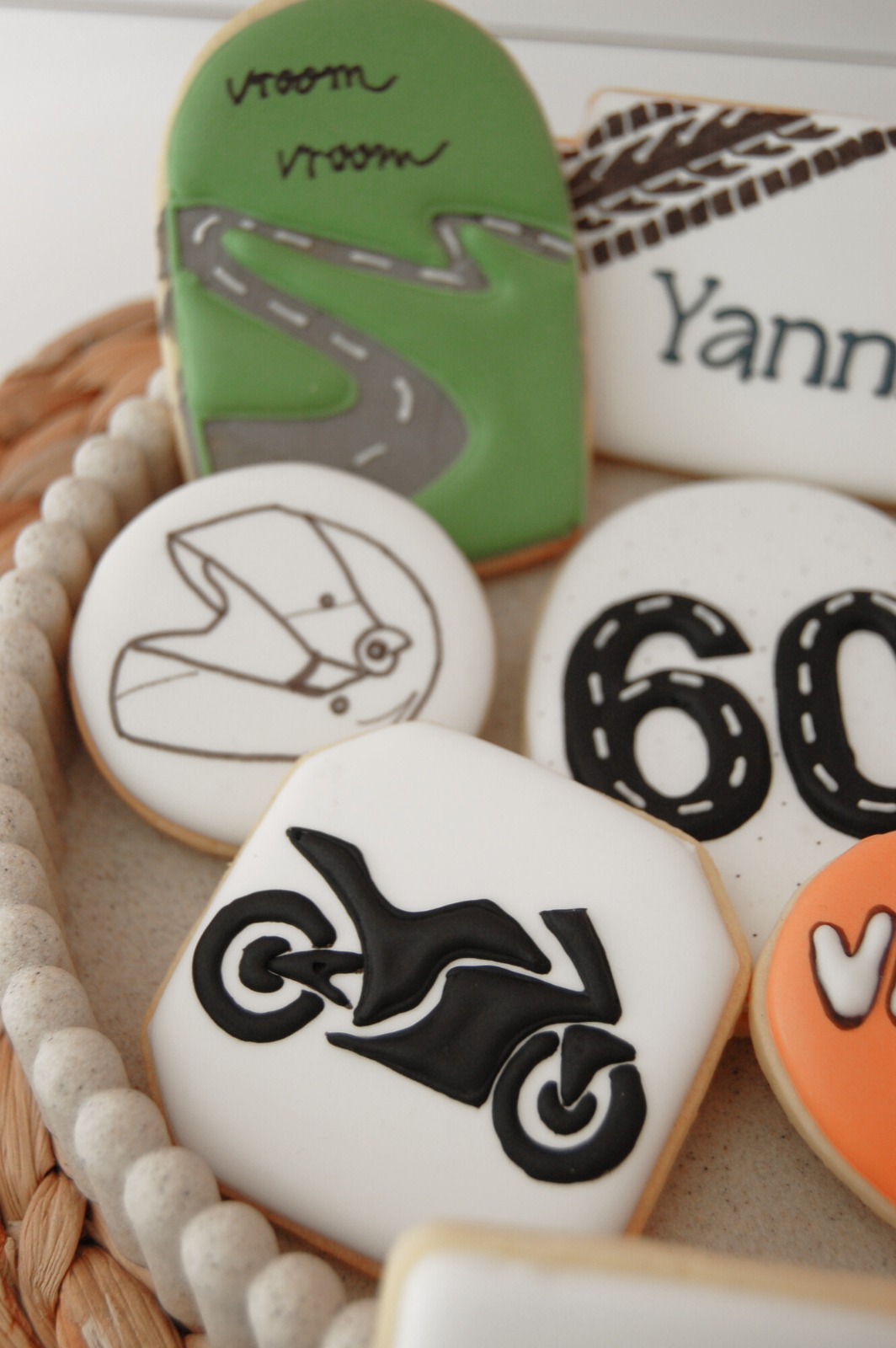 Biscuit moto noir sur glaçage blanc, entouré de biscuits route et casque