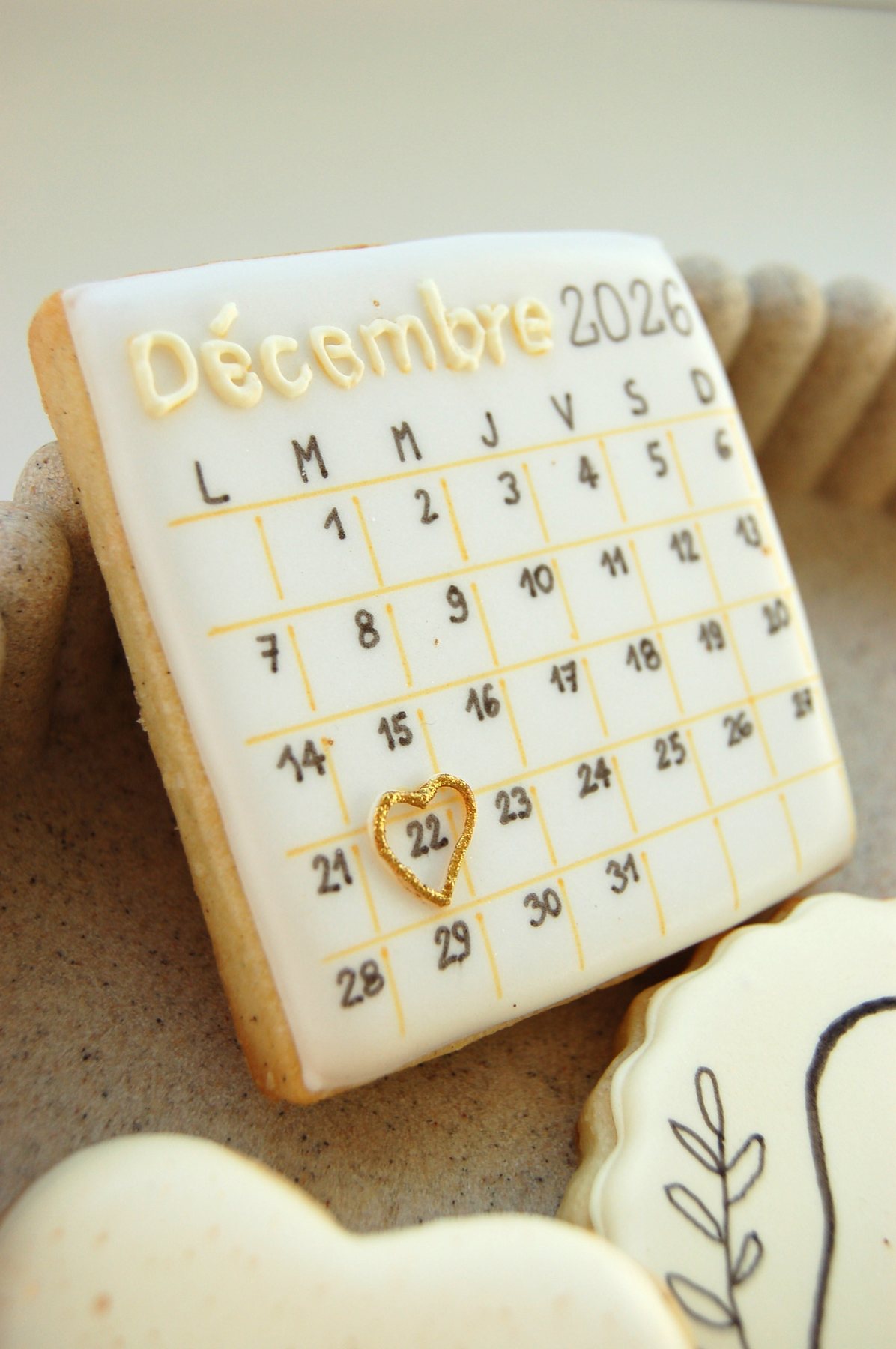 Biscuit calendrier décoré au glaçage, avec une date entourée d'un cœur doré pour annoncer une naissance