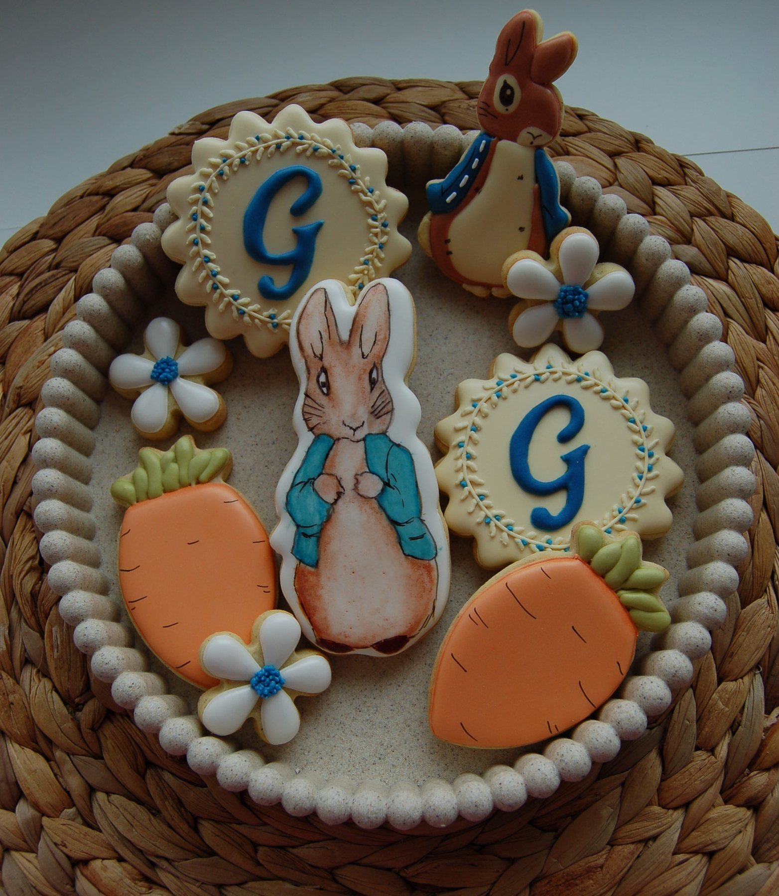 Composition de biscuits de naissance sur plateau tressé : lapin, carottes, marguerites et monogramme G