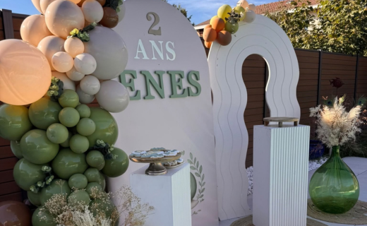 Micro-scénographie personnalisée thème escargot : arche décorée au prénom, guirlande de ballons vert sauge et présentoir de biscuits assortis